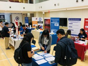 A college fair in Huntsville with booths and attendees.